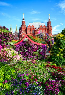 Flowers on Manege Square, Moscow, Russia. Historical Museum (it's written on roof) in background, old Moscow landmark. Scenery of beautiful festive floral decorations in Moscow city center in summer.