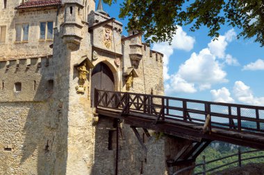 Lichtenstein Castle gates with old wooden bridge in summer, Germany, Europe. This famous castle is landmark of Schwarzwald. Gothic castle entrance against blue sky in Baden-Wurttemberg. clipart