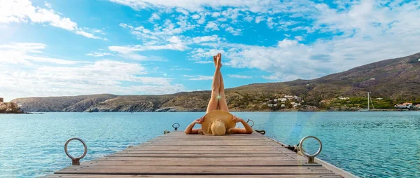 美しいターコイズブルーの海で木製のドックで足でリラックスした女性 リラクゼーションと観光のコンセプト — ストック写真
