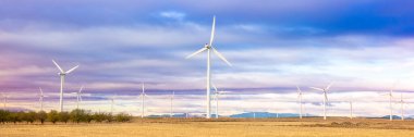 Rüzgar türbinleri gün batımında gökyüzünde. Rüzgar jeneratörlü güzel dağ manzarası türbinler afişi