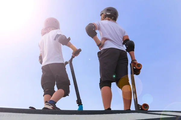 两名儿童与滑板车和滑板在滑板上 活跃的年轻人 — 图库照片