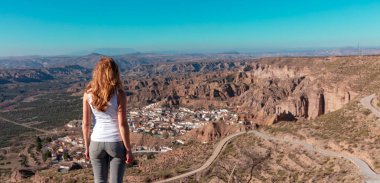 tourism at Gorafe,  woman stands looking at Gorafe city and desert panoramic view