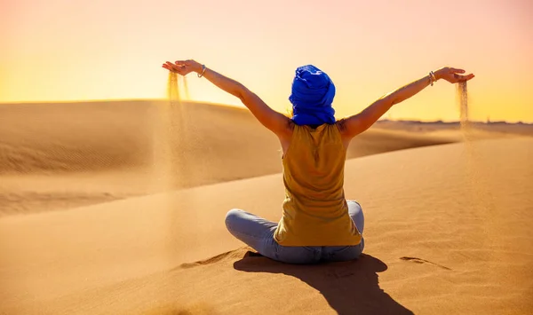 女性観光客でサハラ砂漠で日没時に手に砂を持っている — ストック写真