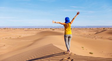 Sahra çölünde kumulda yürüyen bir kadın turist.