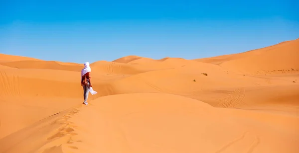 モロッコのサハラ砂漠を白い織物で飛ぶ若い美しい白人女性 — ストック写真