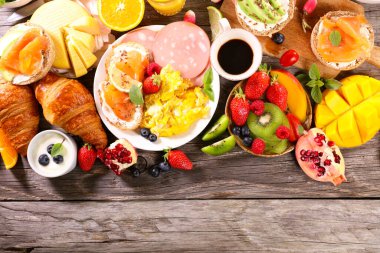 Yumurtalı sağlıklı kahvaltı, tost, kruvasan, taze meyve ve kahve fincanı.