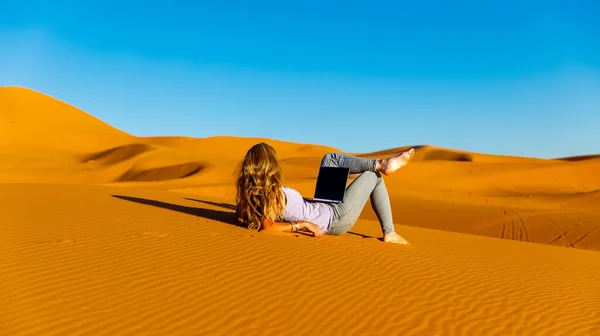 無料の幸せなインスピレーションを受けたフリーランサーの女の子は 砂漠の日没時にコンピュータでリモートワークを楽しんでいます オンライン作業 ビジネス フリーランス デジタルノマドの概念 — ストック写真