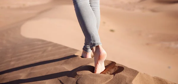 close up on woman legs walking on sand dune in the desert