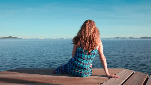 美しい女性は木製の桟橋に座って海を見て リラックスしたコンセプト — ストック写真