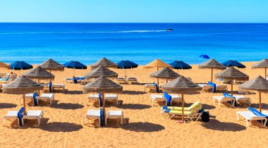 Güneş yatağı ve rood şemsiyeli yaz tatili plajı Portekiz, Algarve