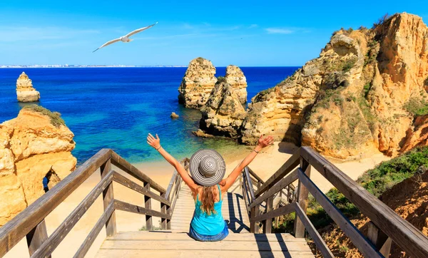 美しいビーチへの歩道橋の上に座っている幸せな女性観光客プライア カミロ Ponta Piedad アルガルヴェビーチ ポルトガルの観光 — ストック写真