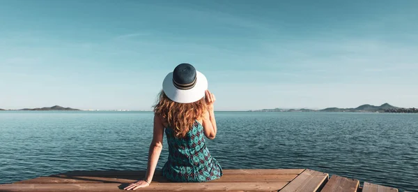 女性は木製の桟橋に座って海を見て — ストック写真