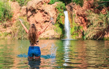 Portekiz 'de tropikal şelalenin tadını çıkaran kadın turist.