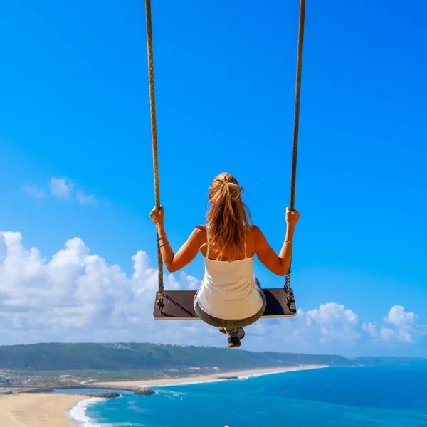海や海を望む青い空を飛ぶスイングに座っている女性 リラックスしたコンセプト — ストック写真
