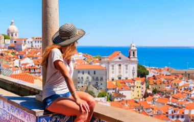 Balkonda oturan kadın turist, Lisbon- Portekiz 'in panoramik çatı manzarasına bakıyor.