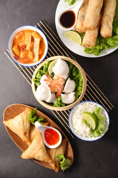 selection of asian food- spring roll, samosa, soup- top view