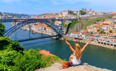 Kolları havada bir kadın ünlü demir köprünün ve Portekiz 'deki eski şehir turizminin güzel panoramik manzarasının keyfini çıkarıyor, Porto' ya seyahat ediyor.