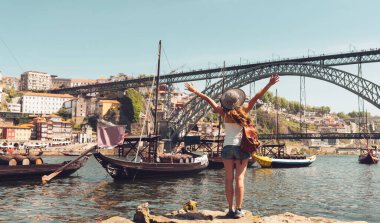 Porto, Portekiz 'i ziyaret eden mutlu kadın turist. Porto şehrinin manzarası, ünlü briç, Douro nehri ve gondolcu teknesi.