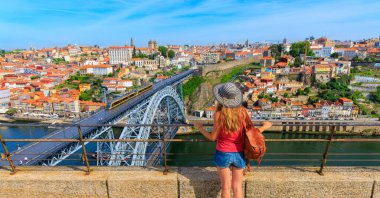 Porto-Portekiz 'in panoramik şehir manzarasında ünlü Luiz Köprüsü ve Douro nehri ile gezen kadın turist.