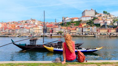 Gezgin kadın turist Douro nehri ve Porto şehri Portekiz 'de geleneksel teknenin tadını çıkarıyor.