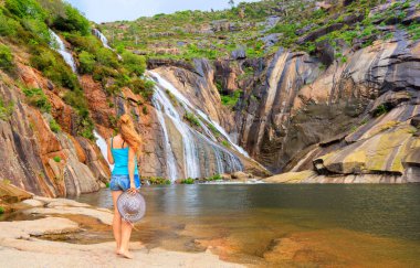 Etkileyici bir şelaleye bakan kadın turist İspanya 'daki Galiçya - Ezaro