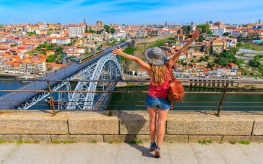 Kolları havada bir kadın turist Porto şehrinin güzel manzarasının ve ünlü demir köprünün tadını çıkarıyor- Portekiz 'de yaz gezisi, tatil, turizm