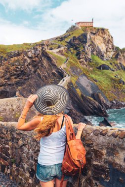 İspanya 'daki San Juan de Gaztelugatxe' nin etkileyici ve görkemli manzarasının tadını çıkaran bir turist.