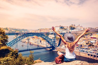 Kolları havada gezen gezgin kadın Porto şehrinin, eski şehrin ve ünlü köprüsü Portekiz 'in panoramik manzarasının keyfini çıkarıyor.