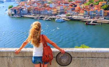 Porto şehri ve Douro nehrinin panoramik manzarasından hoşlanan kadın turist Portekiz