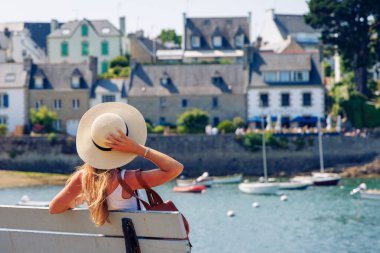 İngiltere 'de tipik bir balıkçı köyüne bakan beyaz şapkalı bir kadın turist. Fransa (Sainte Marine, Combrit)