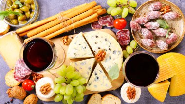 Bir bardak kırmızı şarap, çeşitli peynirler ve sosisler açık büfe yemekleri, atıştırmalıklar.