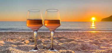 Gün batımında sahilde bir kadeh şarap