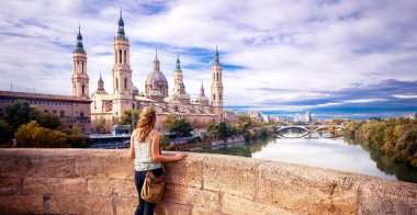 Zaragoza, günbatımında Panorama City manzarası. Gün batımında katedrale bakan kadın turist.
