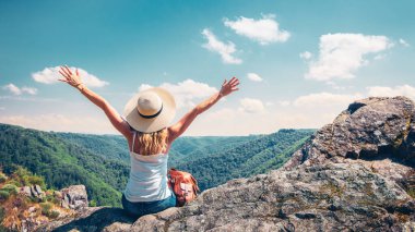 Şapkalı ve sırt çantalı kadın dağın zirvesinde oturuyor güzel manzaranın tadını çıkarıyor (Fransa 'da Dordogne) - Macera, seyahat, özgürlük veya başarılı bir konsept