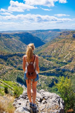 Uçurumun kenarında durmuş güzel panoramik kanyon manzarasının tadını çıkaran bir kadın. Yürüyüş, macera, seyahat konsepti.