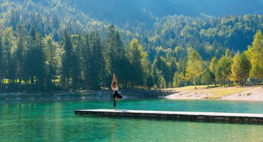 Güzel göl üzerindeki ahşap iskelede yoga - rahatla, zen, meditasyon konsepti