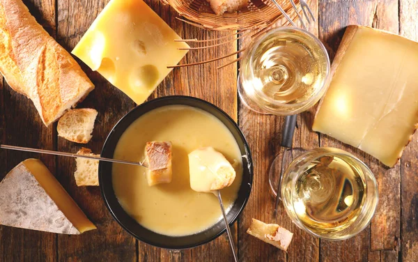 cheese fondue, bread and white wine glasses