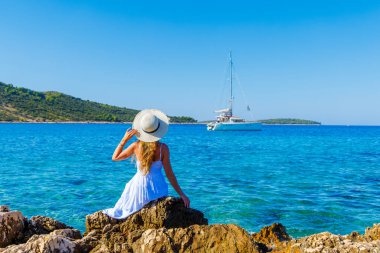 Beyaz elbiseli çekici bir kadın deniz ve yatın tadını çıkarıyor. Seyahat, tatil, tropik tatil, turizm konsepti.