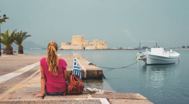 Nafplio limanında oturan sırt çantalı kadın Bourtzi kalesine bakıyor. Yunanistan.