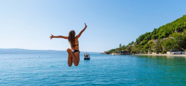 Suya atlayan mutlu genç bir kadın. Tatil, özgürlük, seyahat yeri konsepti.