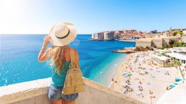 Dubrovnik şehri ve sahilin panoramik manzarasına bakan kadın turist - Hırvatistan