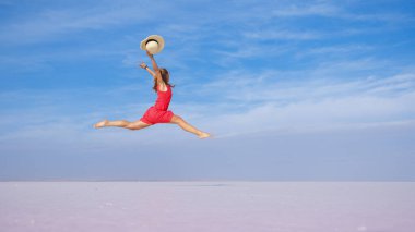 Genç kadın havada zıplıyor Ölü deniz, tuz kıyısı, mavi gökyüzünde tuz gölü