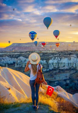 Türkiye 'de Kapadokya' da aşk vadisinde gün doğumunda dalgalanan sıcak hava balonlarının manzarasına bayılan genç bir turist.