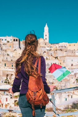 İtalyan bayrağı taşıyan turist kadın İtalya 'daki Matera şehrine bakıyor.
