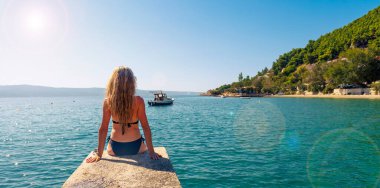 İskelede oturmuş denize bakan bir kadın yaz tatili, dinlenme, seyahat konsepti.