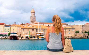 Güvertede oturan kadın turist, Hırvatistan 'ın tipik köyüne bakıyor