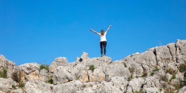 Uçurumdaki mutlu yürüyüşçü kadın, kolları havada ve gökyüzünde