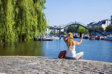 Şehir parkında yerde oturan cep telefonu kullanan bir kadın. 