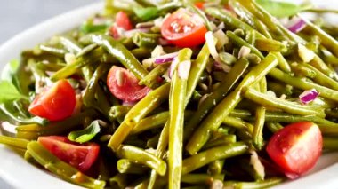 Bir tabak yeşil fasulye, domates ve soğan.