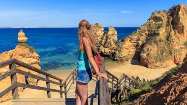 Porugal 'daki Algarve' de kayalıklı plajların panoramik manzarasından hoşlanan güzel bir kadın.